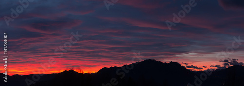Fiery sunset from mountain pick with thin glazes in the sky evening. Fall season. Orobie alps. The summit of Mount Rena. Bergamo Italy. 