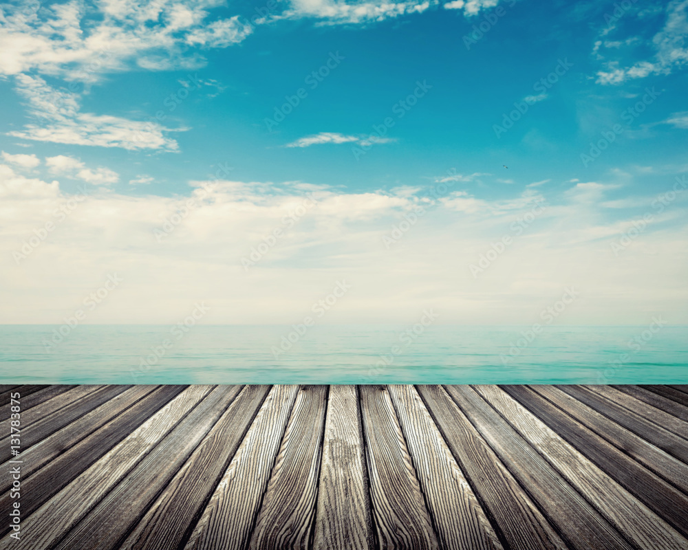 Wooden deck floor against ocean with cloudy sky in background