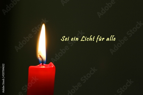 Rote Kerze mit Flamme und dunklem Hintergrund mit deutschem Text