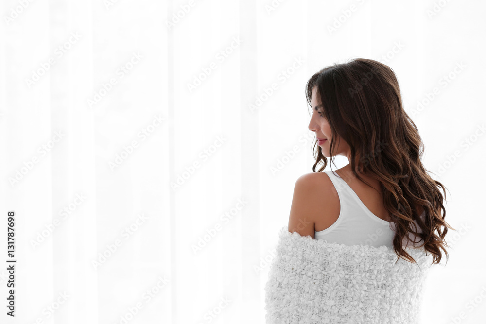 Beautiful woman with soft warm plaid standing near window Beautiful woman with soft warm plaid standing near window