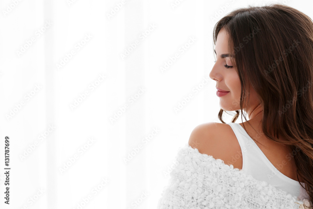 Beautiful woman with soft warm plaid standing near window Beautiful woman with soft warm plaid standing near window
