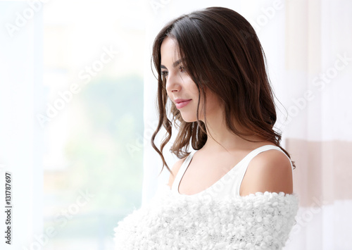 Beautiful woman with soft warm plaid standing near window