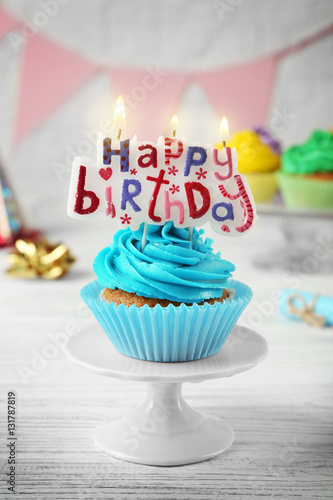 Birthday cupcake with party attributes on white table