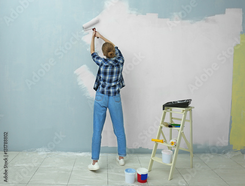 Quadro su tela Beautiful young woman painting wall in room