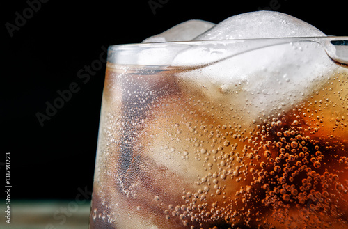 Close up cola glass with drops and ice