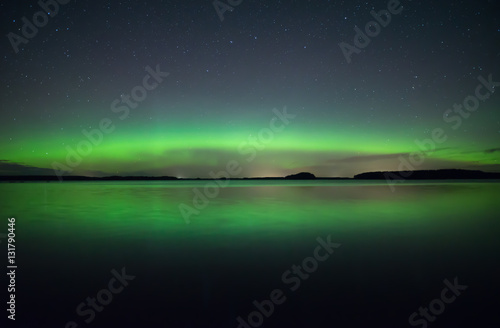 Northern lights dancing over calm lake © Conny Sjostrom