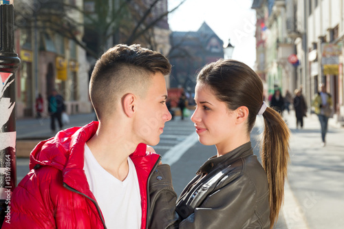 teen couple looking each other, city outdoor, walking street
