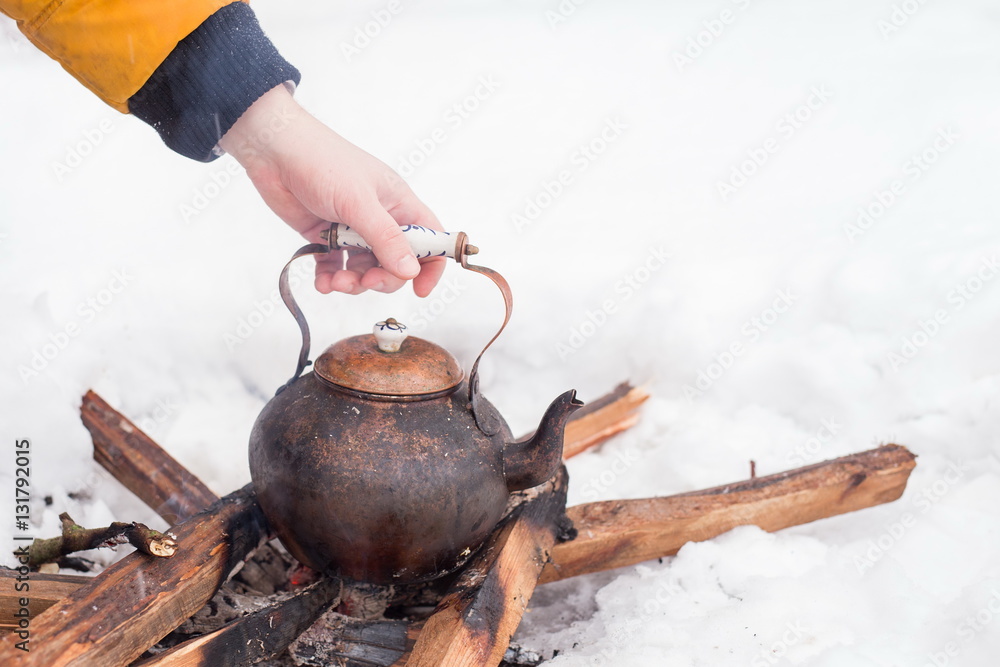 Hand of a man holding copper kettle over an open fire in winter. Boiling  kettle on firewood. Open fire cooking. Snow around. Copy space. Lifestyle,  camping. Stock Photo | Adobe Stock