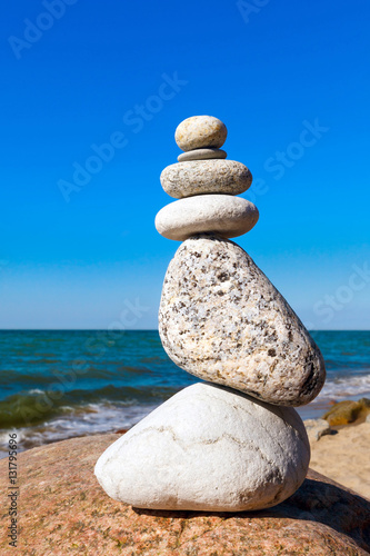 balance of white stones on a background of blue sky and sea