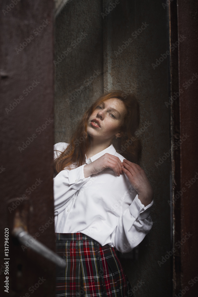 Fototapeta premium Wonderful redhead model with freckles behind the glass door