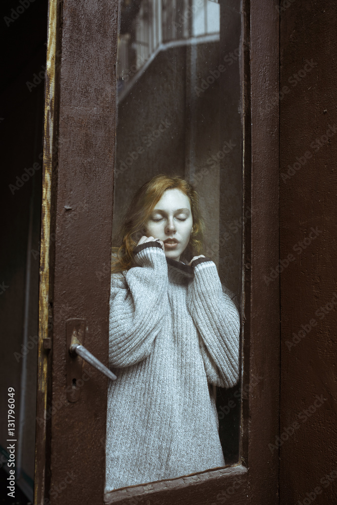 Obraz premium Sensual young model with freckles behind the old glass door
