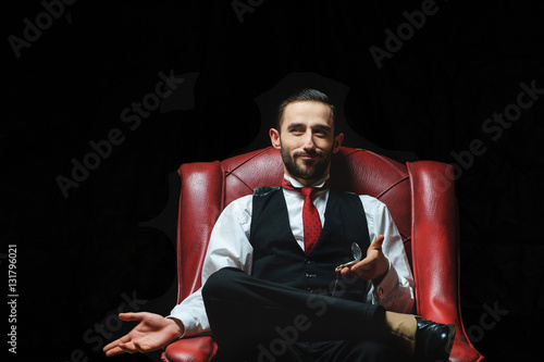 side view of an elegant young businessman smoking a cigarette on black studio background photo