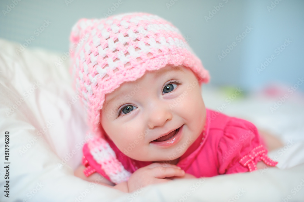 little girl in a knitted hat lying on the bed little girl in a knitted hat lying on the bed