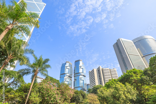 Hong Kong cityscape of modern skyscrapers and towers in the Central business district in a sunny day with blue sky seen from the Hong Kong Park, an green oasis of peace.