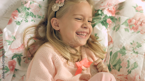 Adorable little girl lying on the bed and laughing gaily