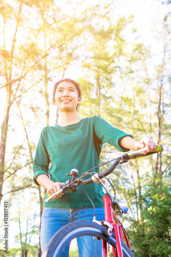 Young asian woman with red bicycle in a park - outdoor portrait