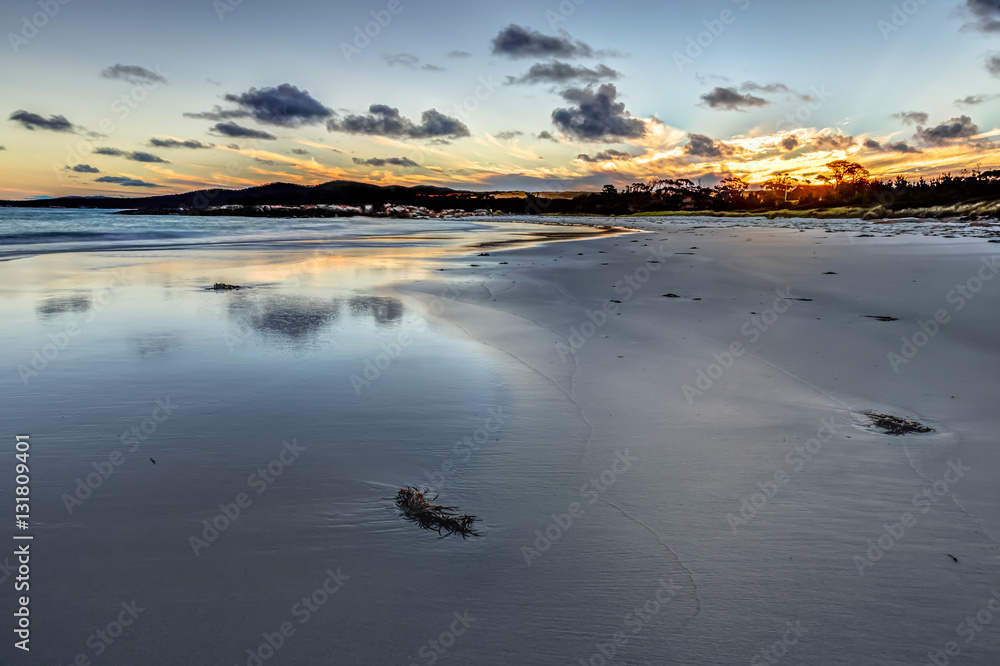 Fototapeta premium Scenic and pristine white sandy beach with turquoise crystal waters and orange lichen covered granite boulders at sunset. The Gardens in the Bay of Fires consevation Area, east coast of Tasmania.