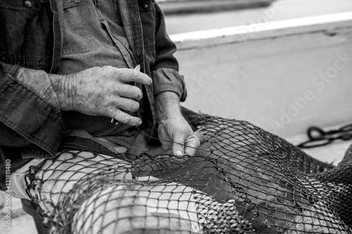 Hands of weathered fisherman mending net © Wollwerth Imagery