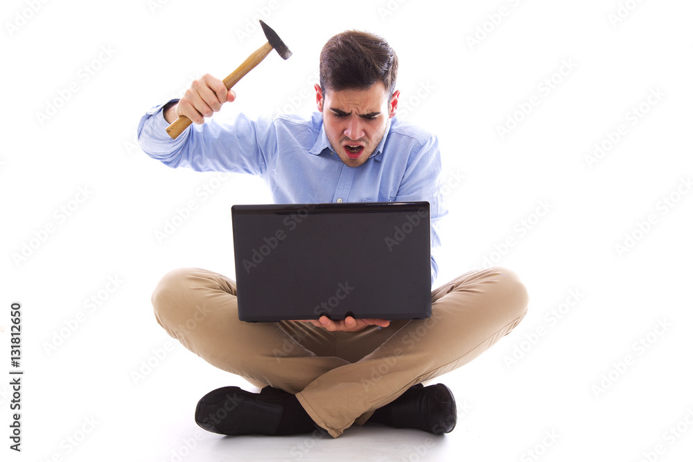 Man sitting on the floor hitting the computer with hammer Man sitting on the floor hitting the computer with hammer