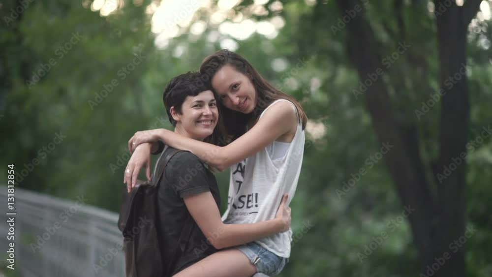 The lesbian sit on a fence and hugs her girlfriend The lesbian sit on a fence and hugs her girlfriend