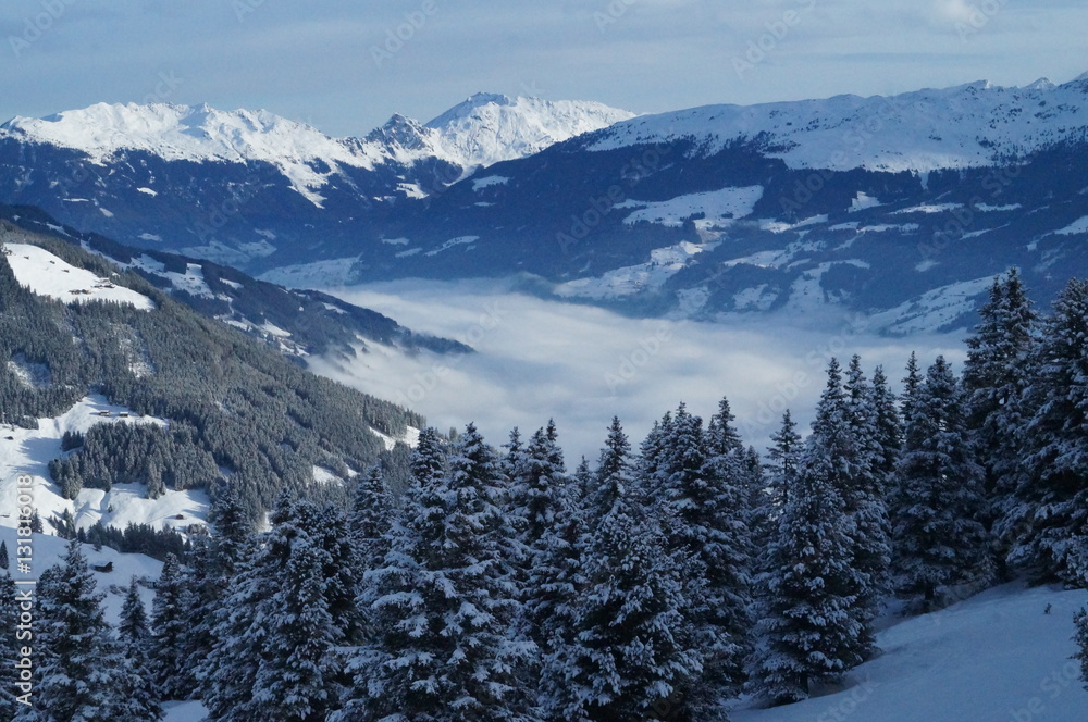 Snowy mountain view of the alps and a valley in the clouds