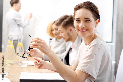 Portret uśmiechniętej kobiety na zebraniu firmowym. Grupa ludzi na spotkaniu w firmie, podczas prezentacji projektu
