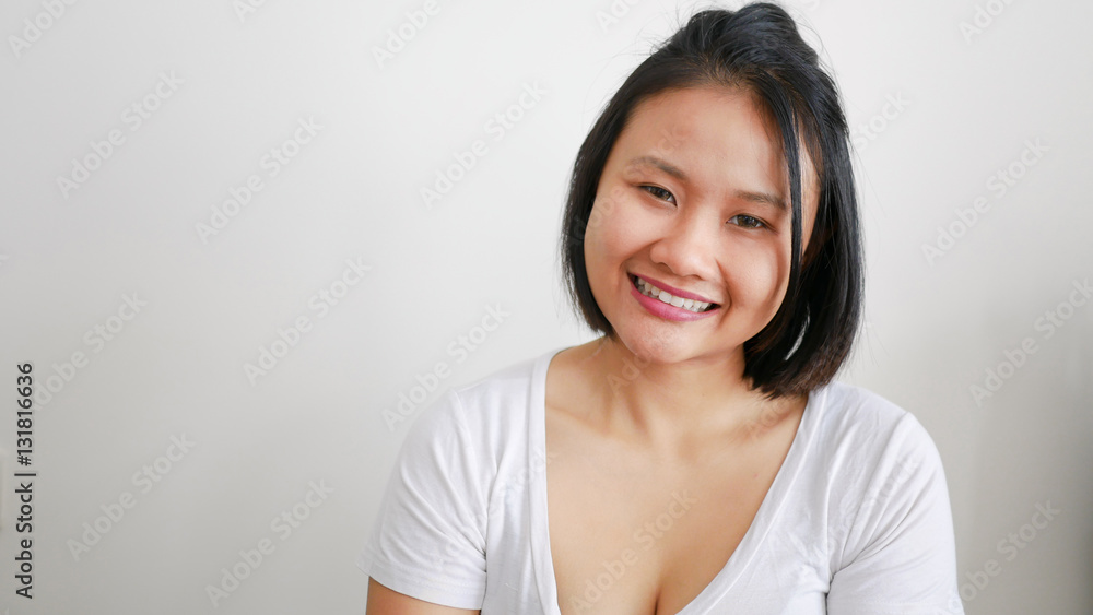 Asian woman wearing white t-shirt smiling on white background Asian woman wearing white t-shirt smiling on white background