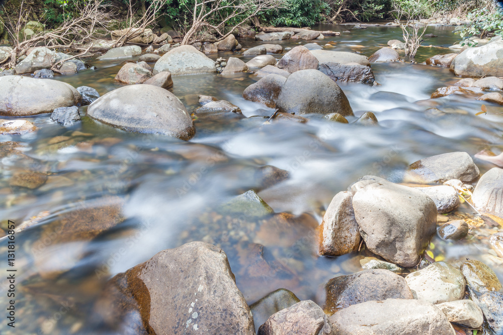 Clear water of stream flowing through natural mountain rocks.