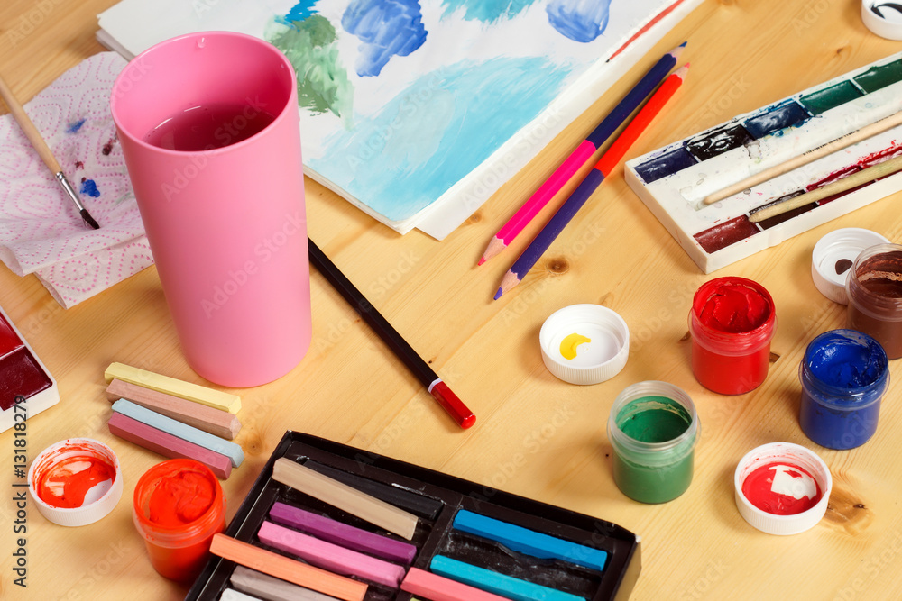 Naklejka premium Different paints and crayons are on the table next to the figure