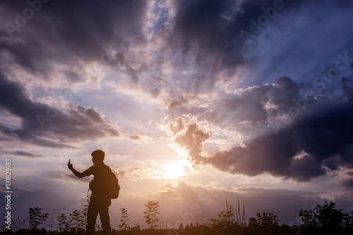 Silhouette man with backpack use smartphone in hands at sunset b