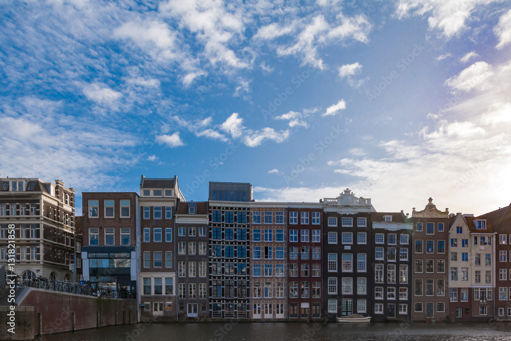 Netherlands, Amsterdam - piece of canal facade with typical houses against blue sky