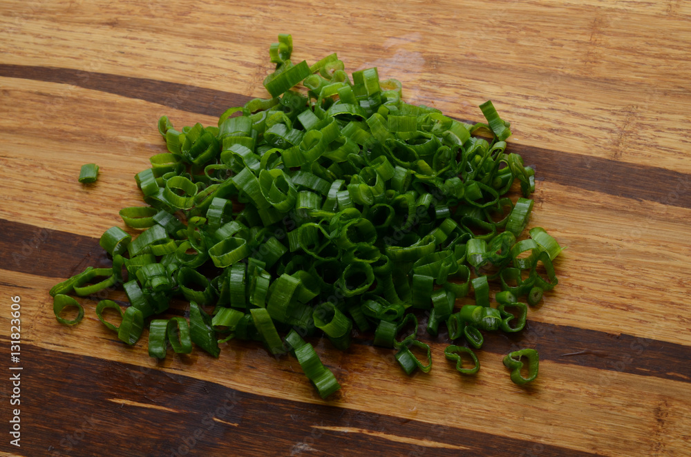Sliced, chopped spring onions, salad onions, green onions or scallions on wood background Sliced, chopped spring onions, salad onions, green onions or scallions on wood background