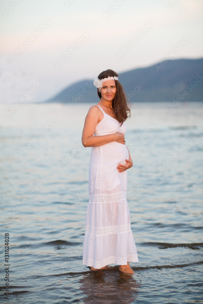 Happy Pregnant woman holding her belly relaxing on the beach
Happy Pregnant woman holding her belly relaxing on the beach