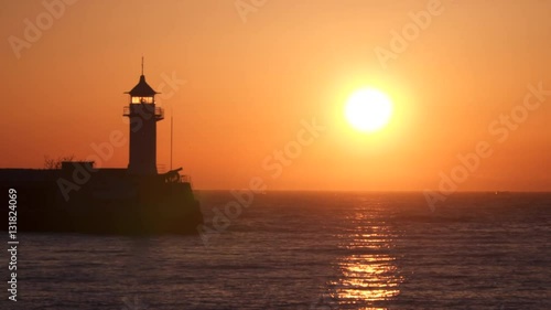 Wallpaper Mural Lighthouse illuminated by the rising sun. The sun is reflected in water Torontodigital.ca