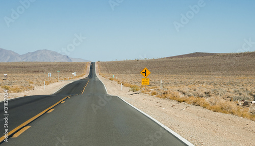 View of a straight section of Saline Valley Road in Death Valley National Park, with arid desert on the road-side.
