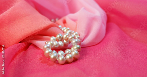 Beads from pearls against the background of pink fabric.