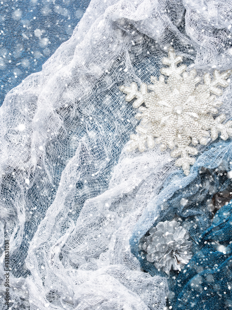 Fototapeta premium Winter christmas background with snow flake and silver textile. Top view. Vertical. Snow falling