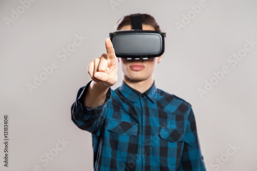 emotional funny man wearing virtual reality goggles. Studio portrait of video game designer wearing VR headset. studio shot isolated on gray background.