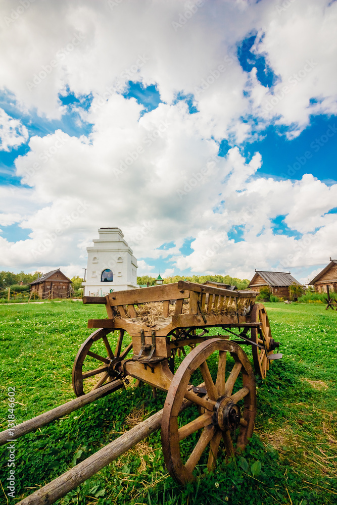 Old wagon in rural landscape on a green grass against a blue sky