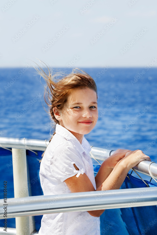 Windblown young girl looks out from a boat rail