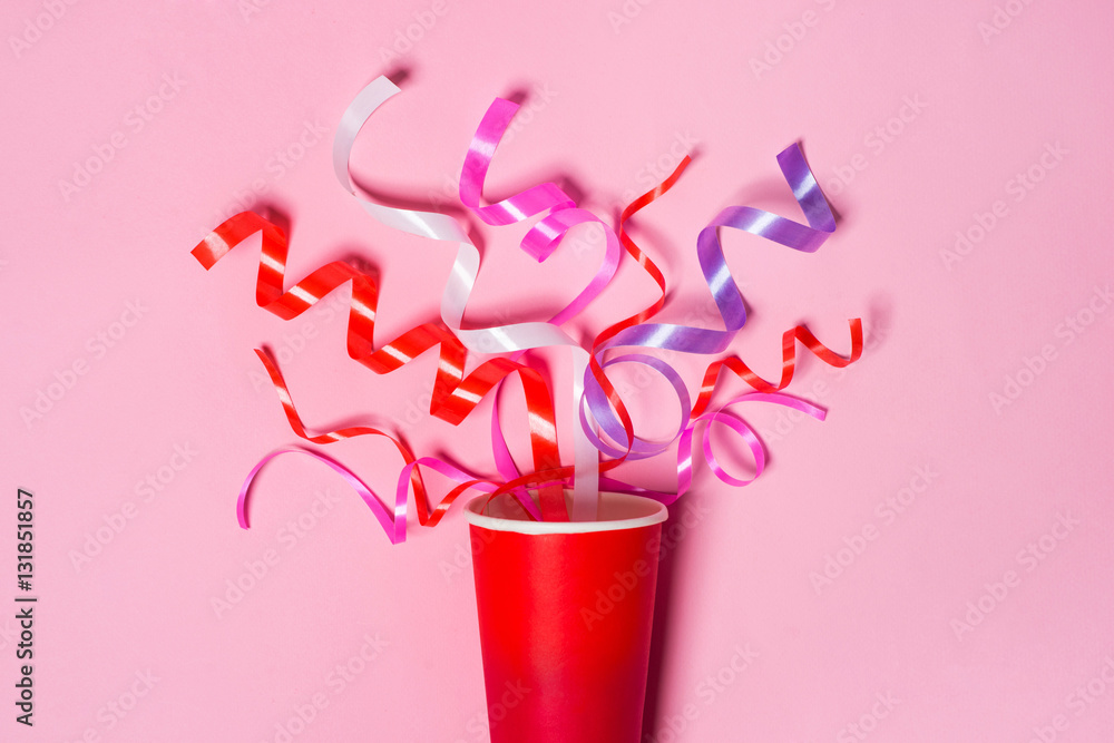Flat lay of Celebration. Paper cup with colorful party streamers