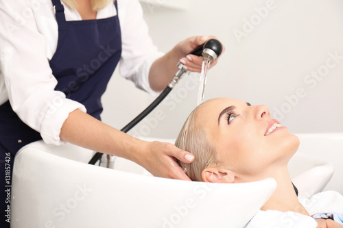 Hairdresser washing woman's hair in salon