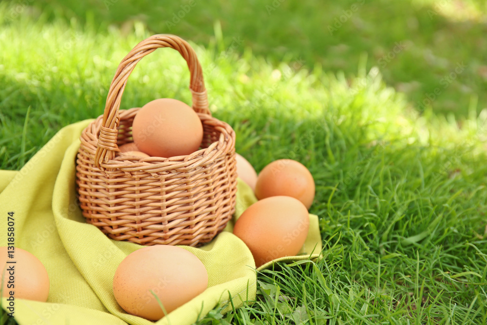 Raw eggs in basket on green grass background Raw eggs in basket on green grass background