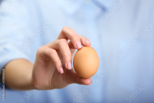 Female hand holding raw egg, closeup