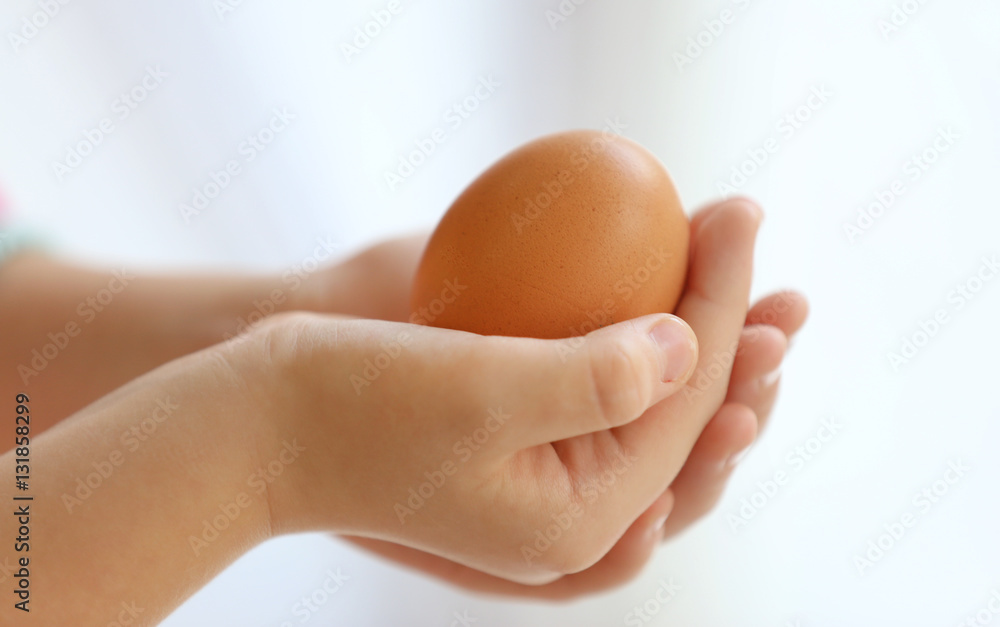 Child hands holding raw egg, closeup Child hands holding raw egg, closeup