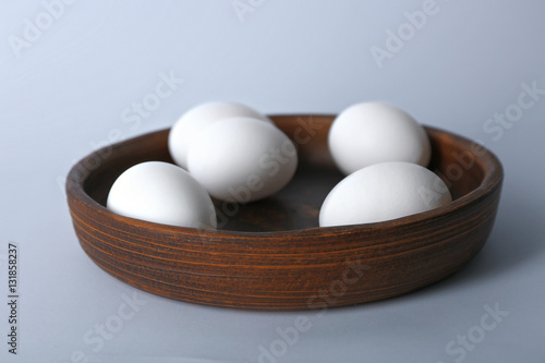 Raw eggs on plate on white background