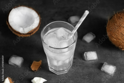 Glass of coconut water and fresh nut on dark background