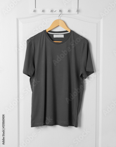 Blank grey t-shirt hanging on white door © Africa Studio