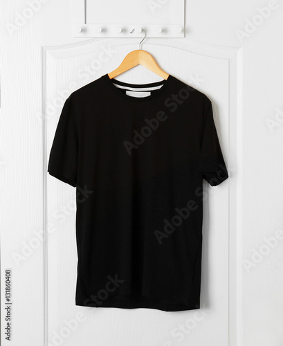 Blank black t-shirt hanging on white door