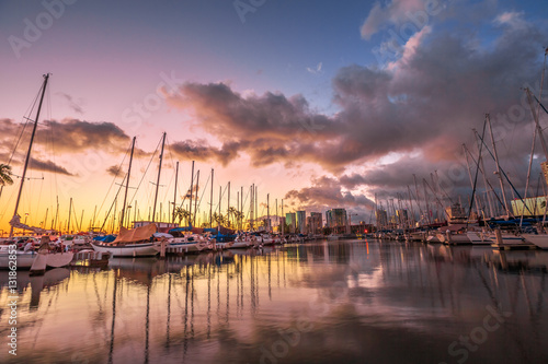 Dramatic landscape of sailing boats and yachts docked at the Ala Wai Harbor, the largest yacht harbor of Hawaii, reflecting in the sea at sunset. Honolulu, Oahu, Hawaii.